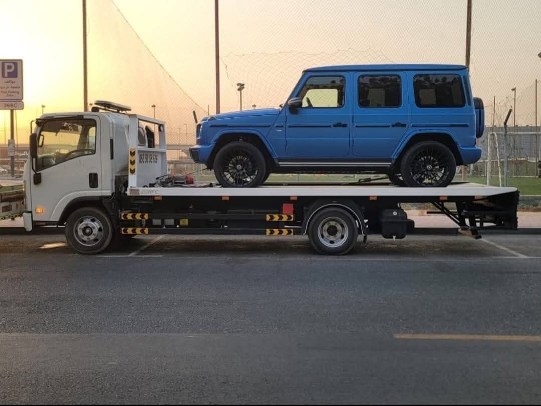 Blue Mercedes G-Class recovery on flatbed tow truck at sunset in Dubai